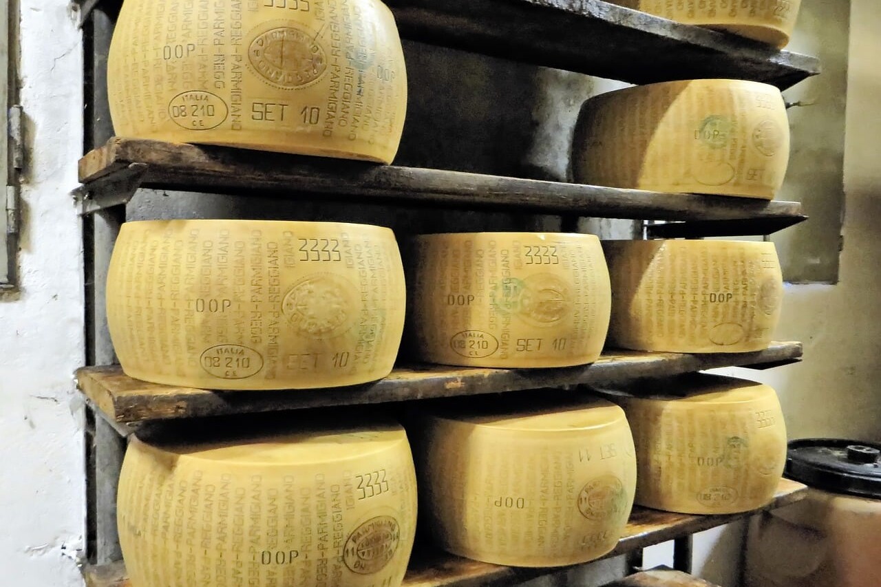 The image displays wheels of Parmigiano-Reggiano cheese, often called the