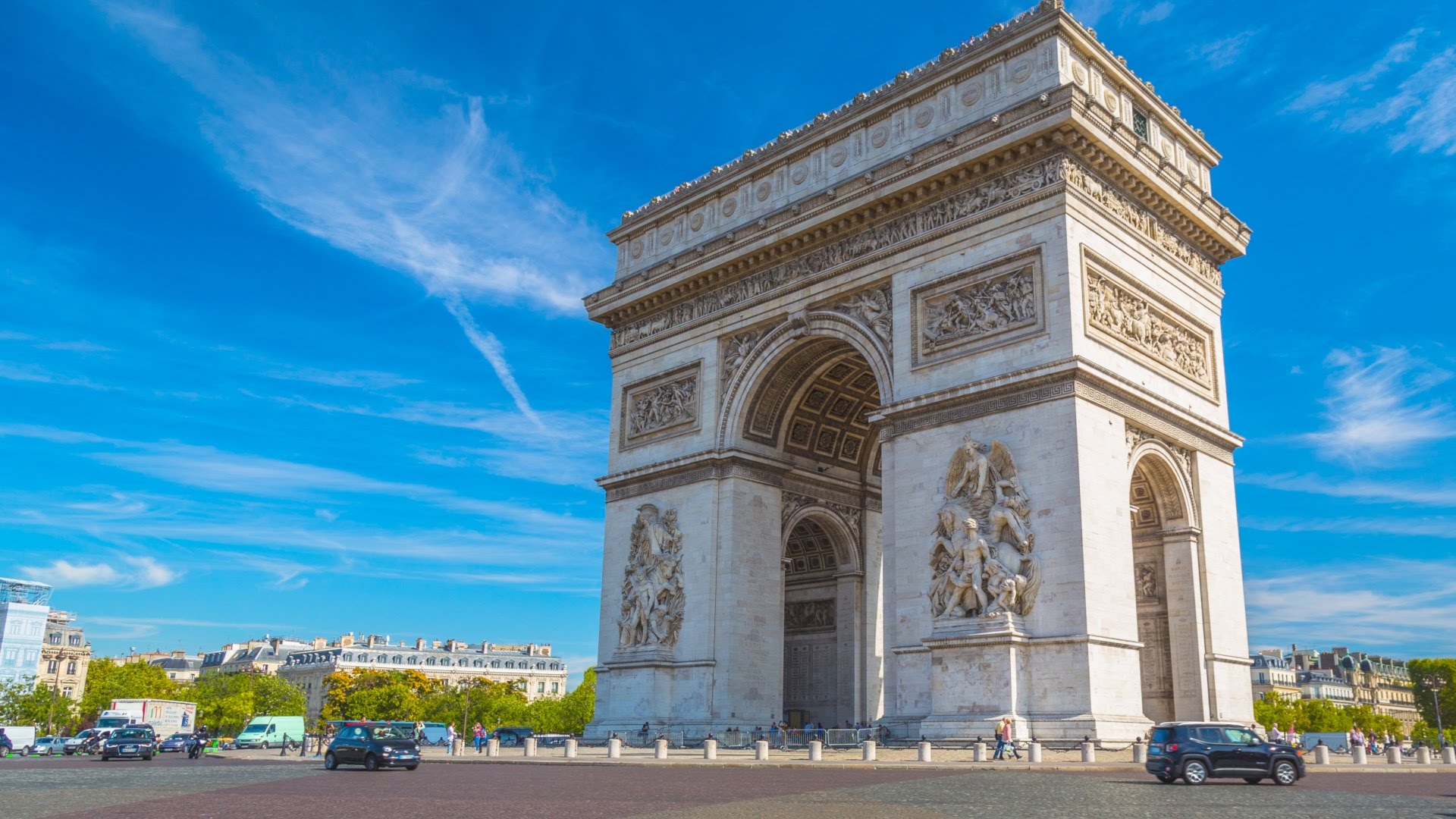  The Arc de Triomphe stands at the center of Paris, its carved stone reliefs honoring French military history under a blue sky 