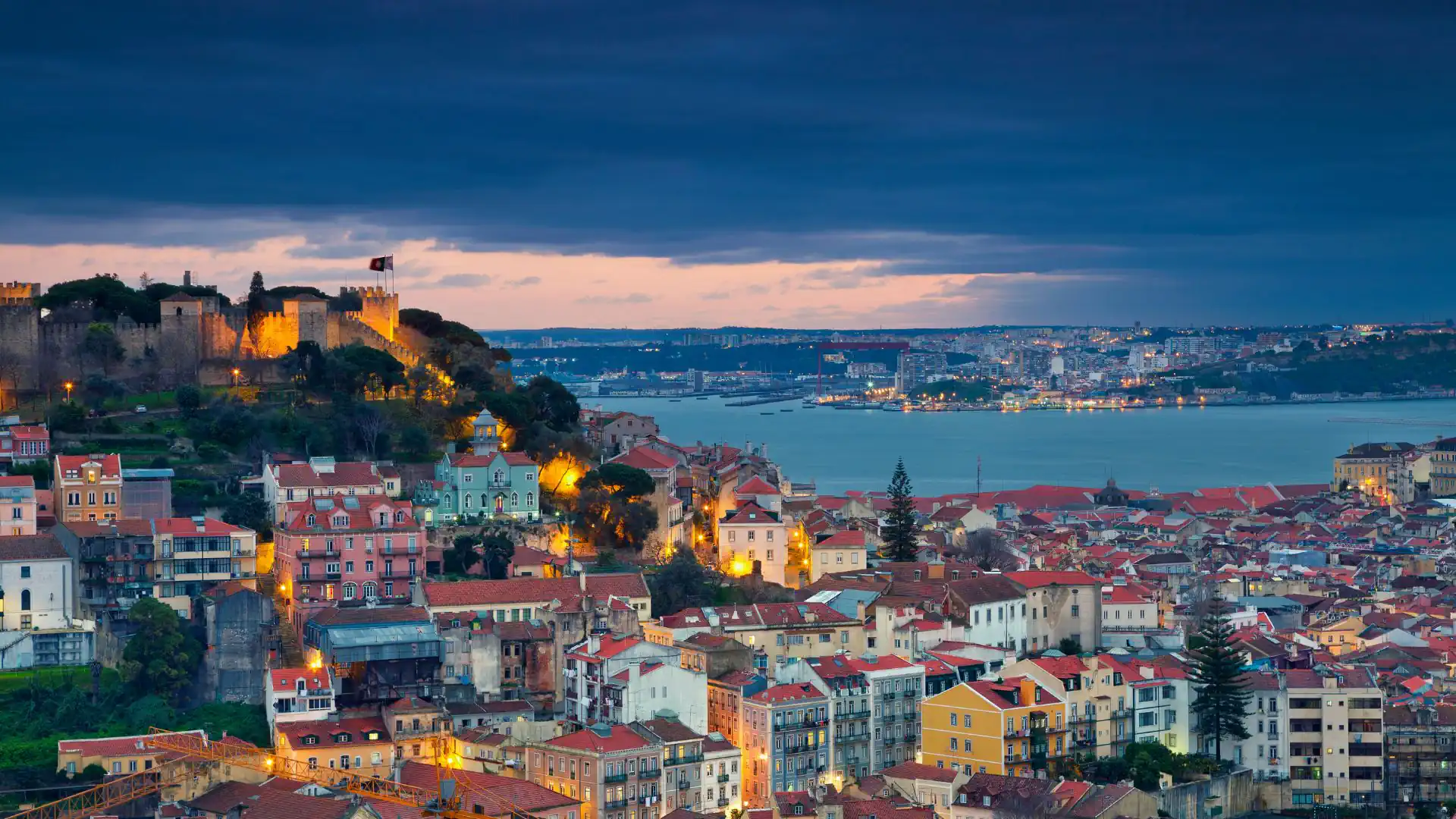 São Jorge Castle overlooks Lisbon’s historic rooftops and the Tagus River as evening falls.