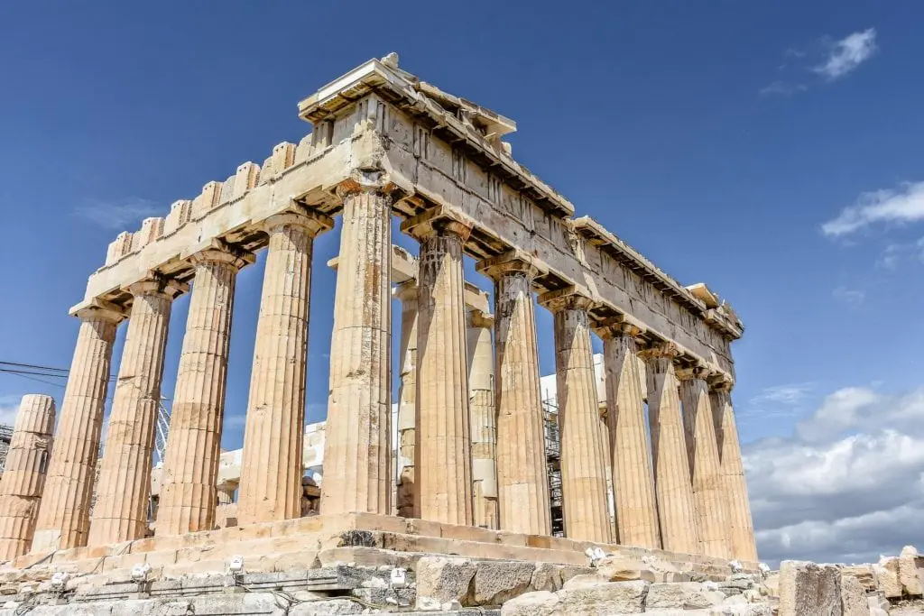 Ionic columns and marble entablature of the Erechtheion temple on the Acropolis in Athens, Greece, against a blue sky