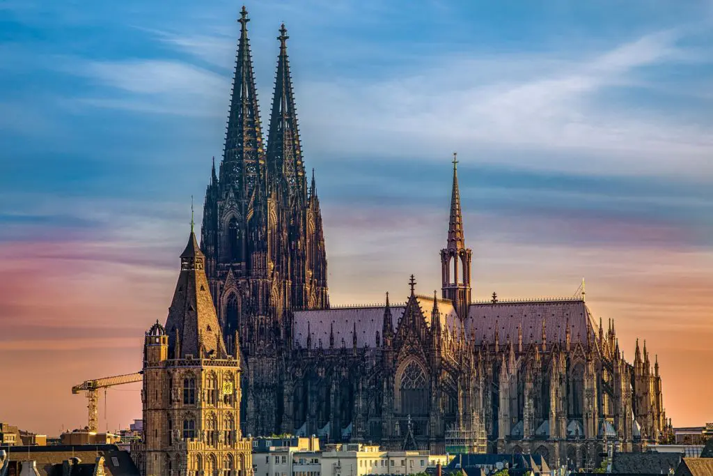 Cologne Cathedral's soaring twin spires dominate the city skyline at sunset, a UNESCO World Heritage site and Germany's most visited landmark