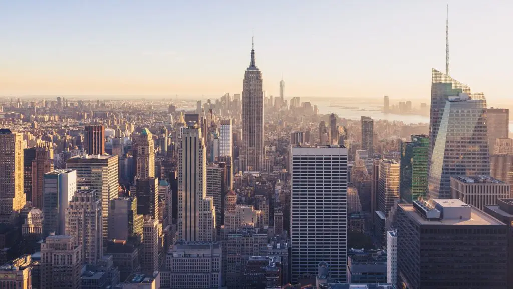The Empire State Building rises above the dense Midtown Manhattan grid in this aerial view, with both the Hudson and East Rivers framing the island beyond
