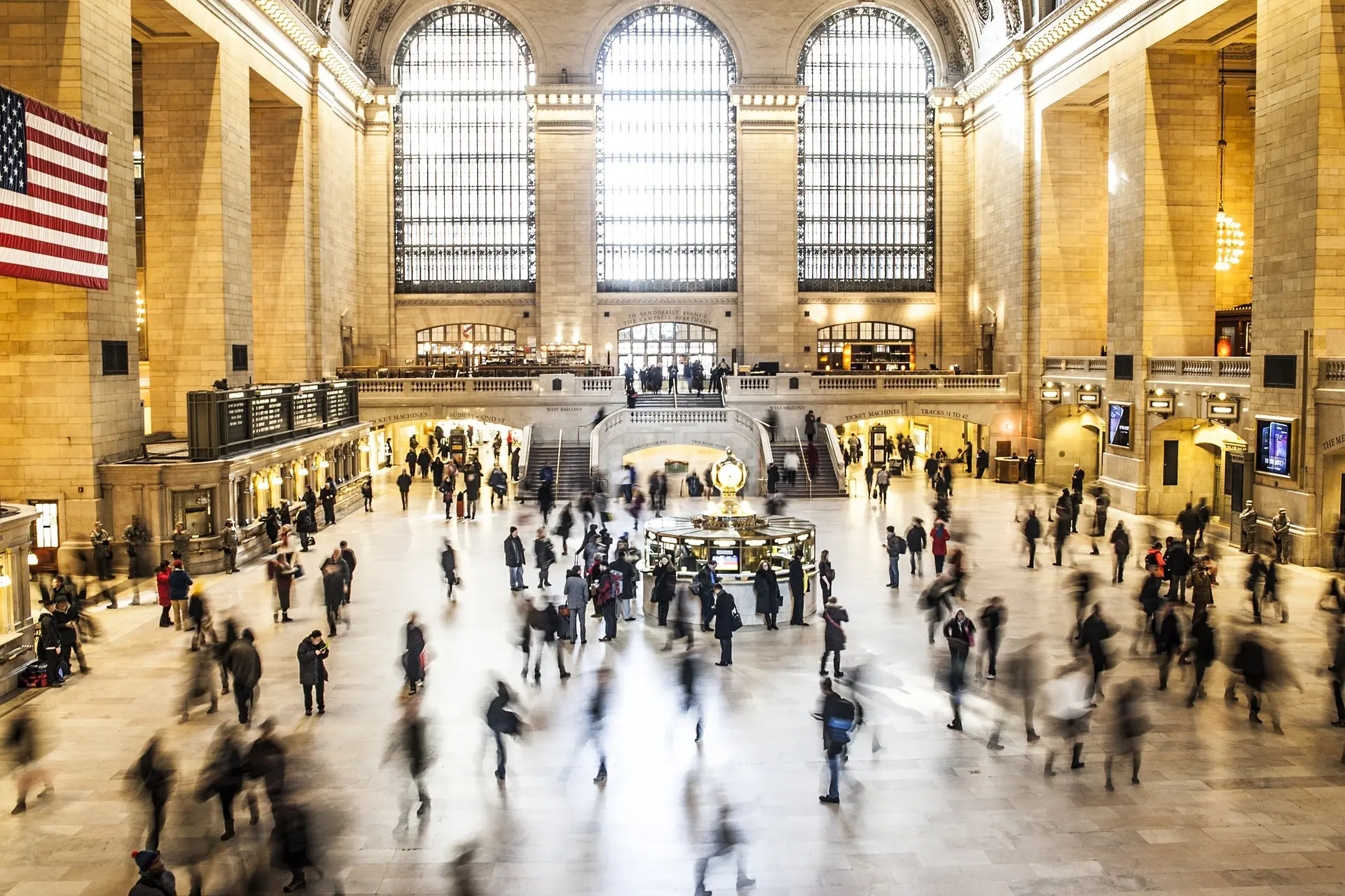 Grand Central Terminal's magnificent main concourse bustles with commuters beneath its famous celestial ceiling and towering arched windows, a masterpiece of Beaux-Arts architecture