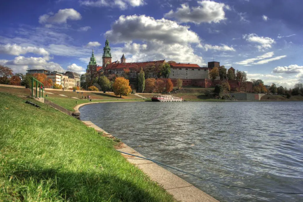 An ivy-covered stone gateway at Wawel Castle in Krakow draws visitors along a winding path through the castle's ancient grounds
