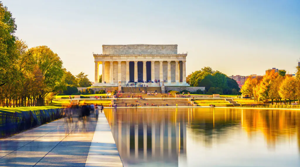 The Lincoln Memorial and its perfect reflection stretch across the National Mall Reflecting Pool at golden hour in Washington DC