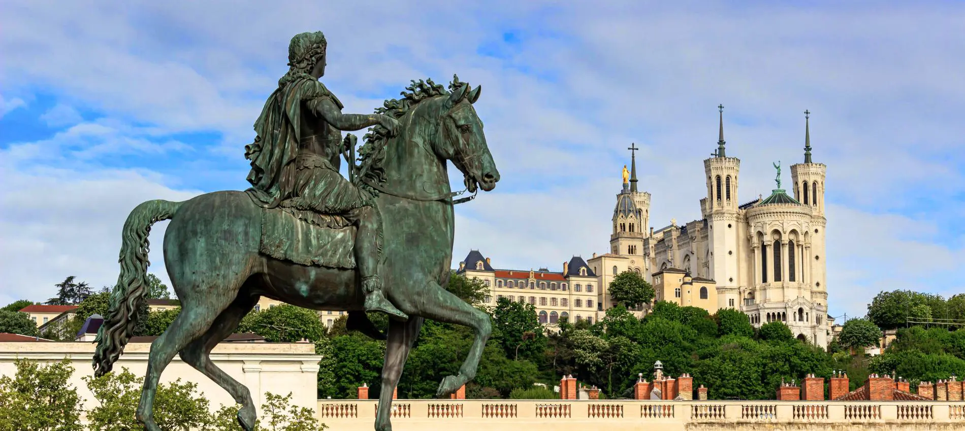 The bronze equestrian statue of Louis XIV in Place Bellecour frames the Basilica of Notre Dame de Fourviere on Lyon's hilltop