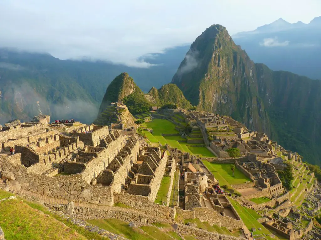 The iconic Inca citadel of Machu Picchu emerges from the morning mist with Huayna Picchu rising dramatically behind
