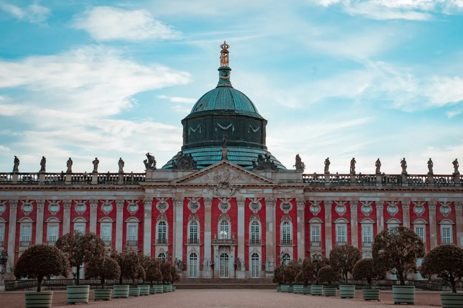 The grand New Palace at Sanssouci in Potsdam displays the full ambition of Prussian Baroque architecture, with its copper dome and rooftop sculptures
