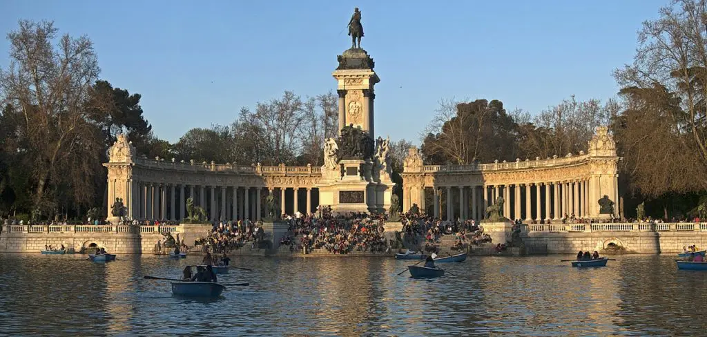 The Crystal Palace in Madrid's Retiro Park is reflected in the lake before it, a delicate iron and glass structure built in 1887 for a colonial exhibition