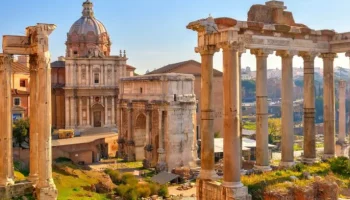 The Roman Forum in Rome at golden hour, with the Temple of Saturn columns and Arch of Septimius Severus rising above the ancient ruins