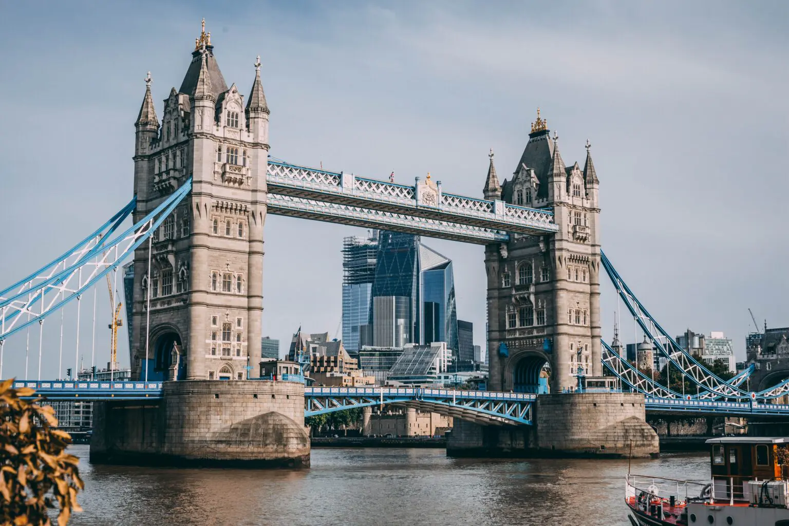 Tower Bridge stands over the Thames with London's modern skyline rising behind its Victorian stone towers